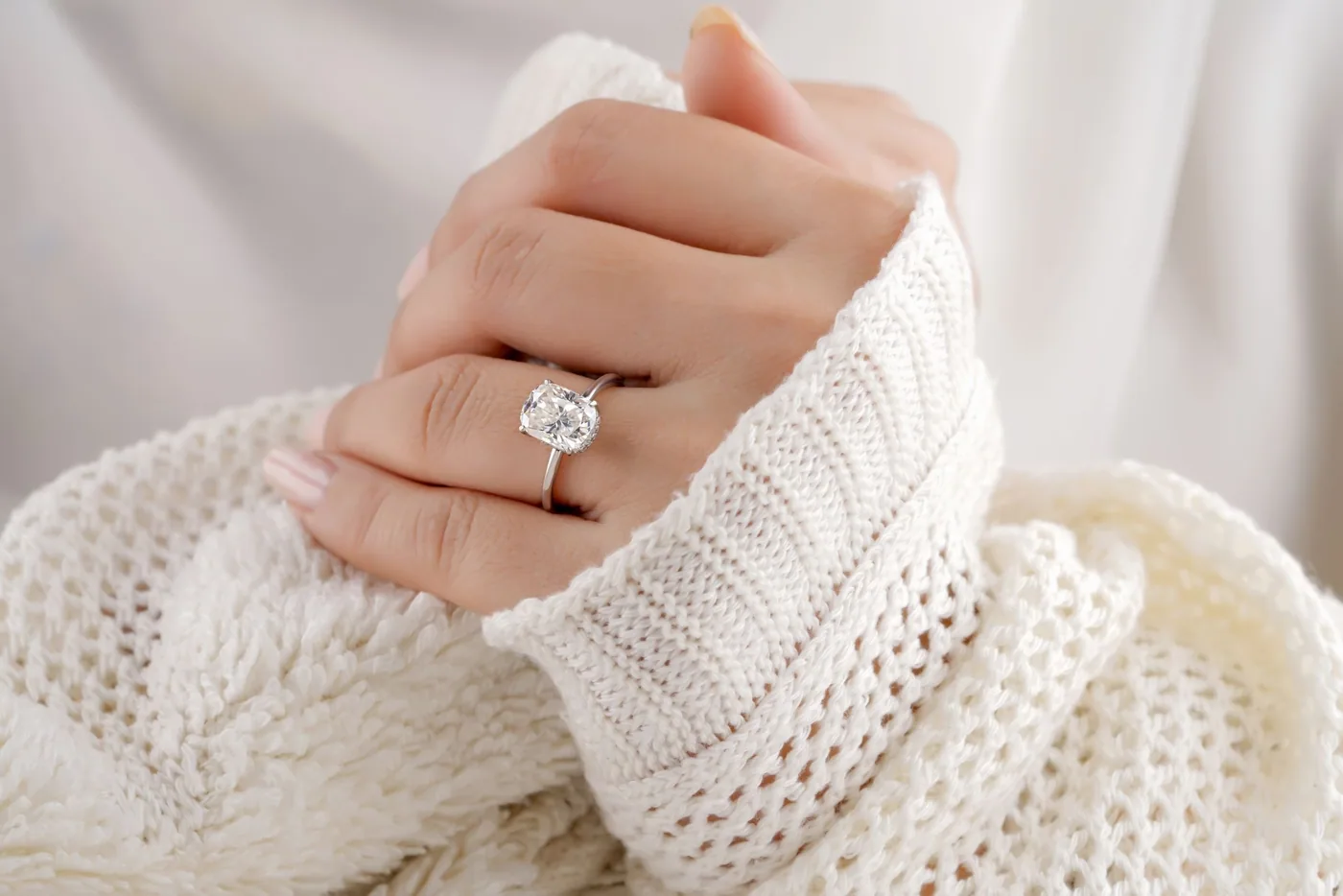 A diamond solitaire ring worn with a cream knit sleeve