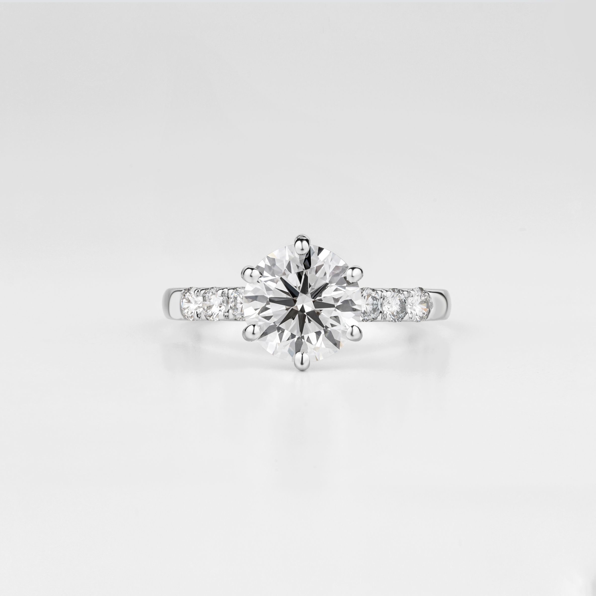 A round diamond solitaire ring on a pale grey ground